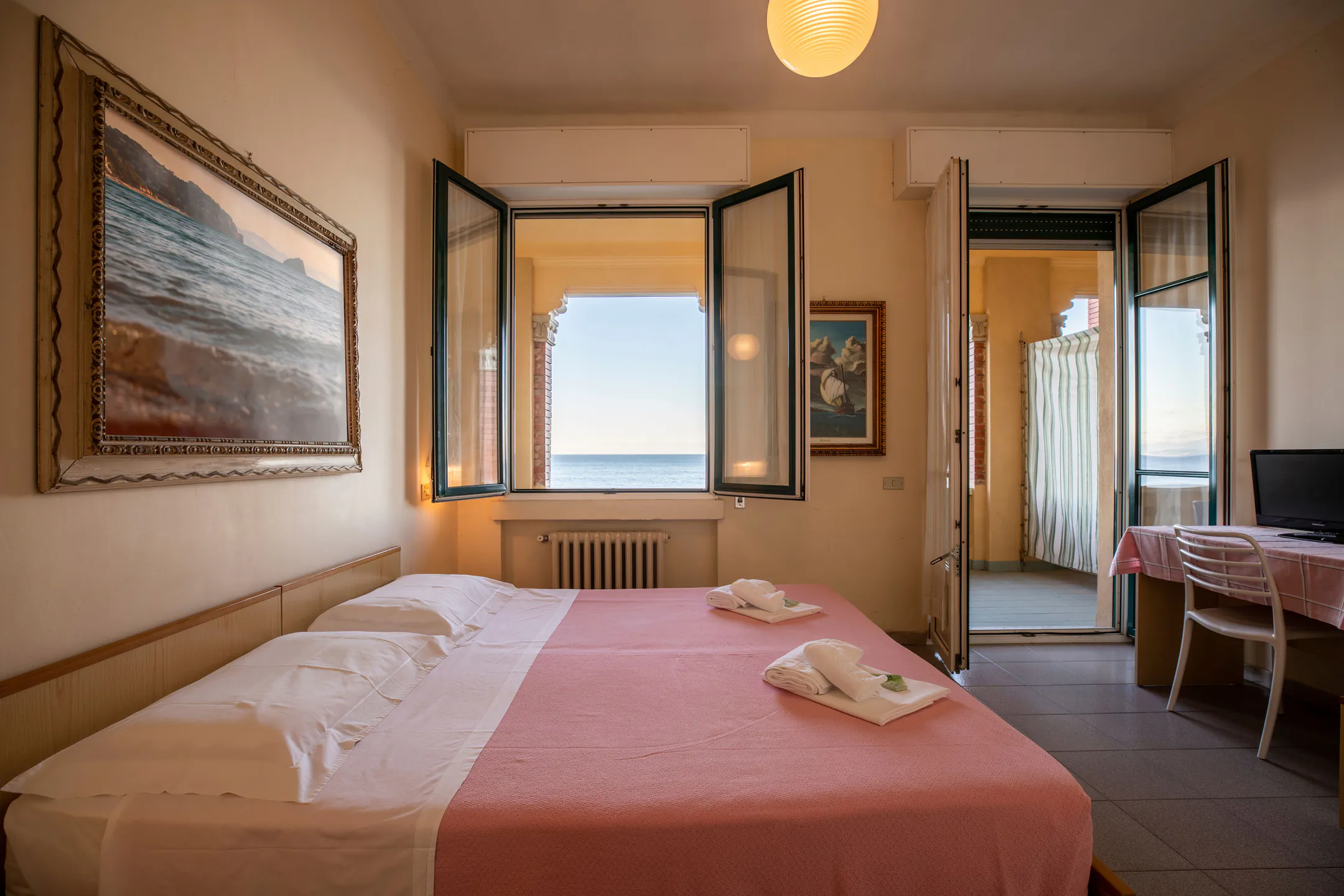 Camera doppia con letto matrimoniale, finestre aperte sul mare e un grande quadro alla parete